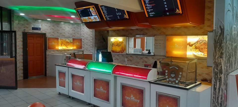 Inside Cane Cutters: the service counter with lit domes, menu screens on the wall and a trophy on the counter
